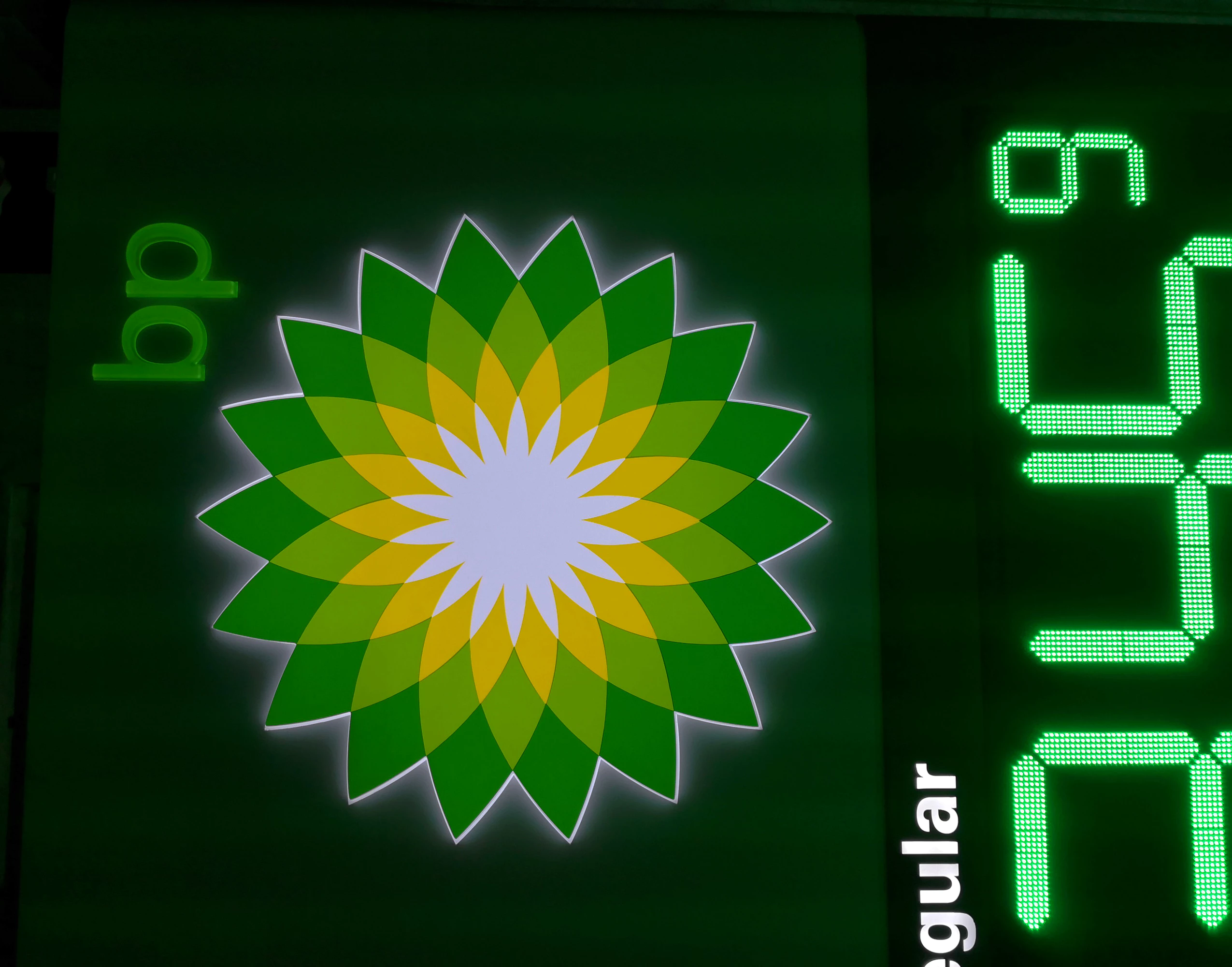Close-up of BP helios logo and green digital numbers on LED gas station sign