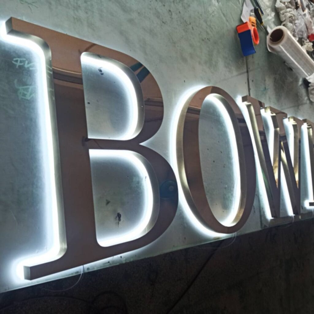 Stainless steel backlit letter factory product showing "Bowl" sign with bright white halo lighting effect