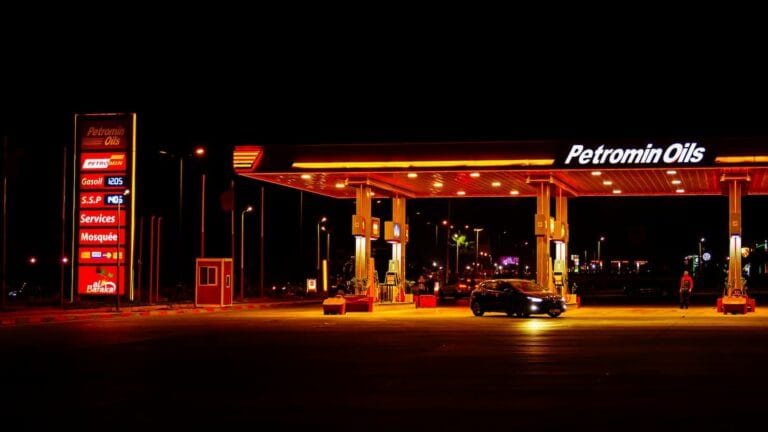 Illuminated Petromin Oils gas station pylon sign and forecourt night scene